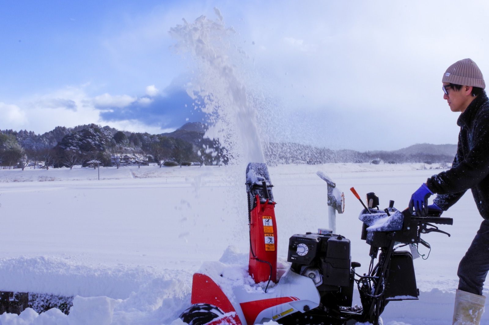 雪景色の中で除雪機を操作する様子（イメージ写真）