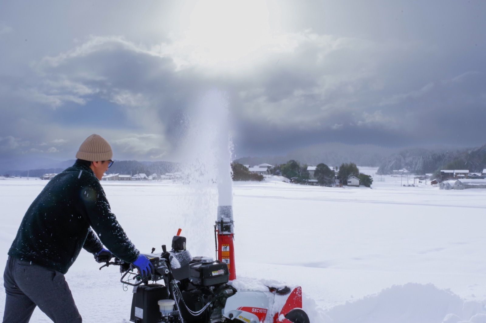 雪を飛ばしながら除雪機を操作する様子（イメージ写真）