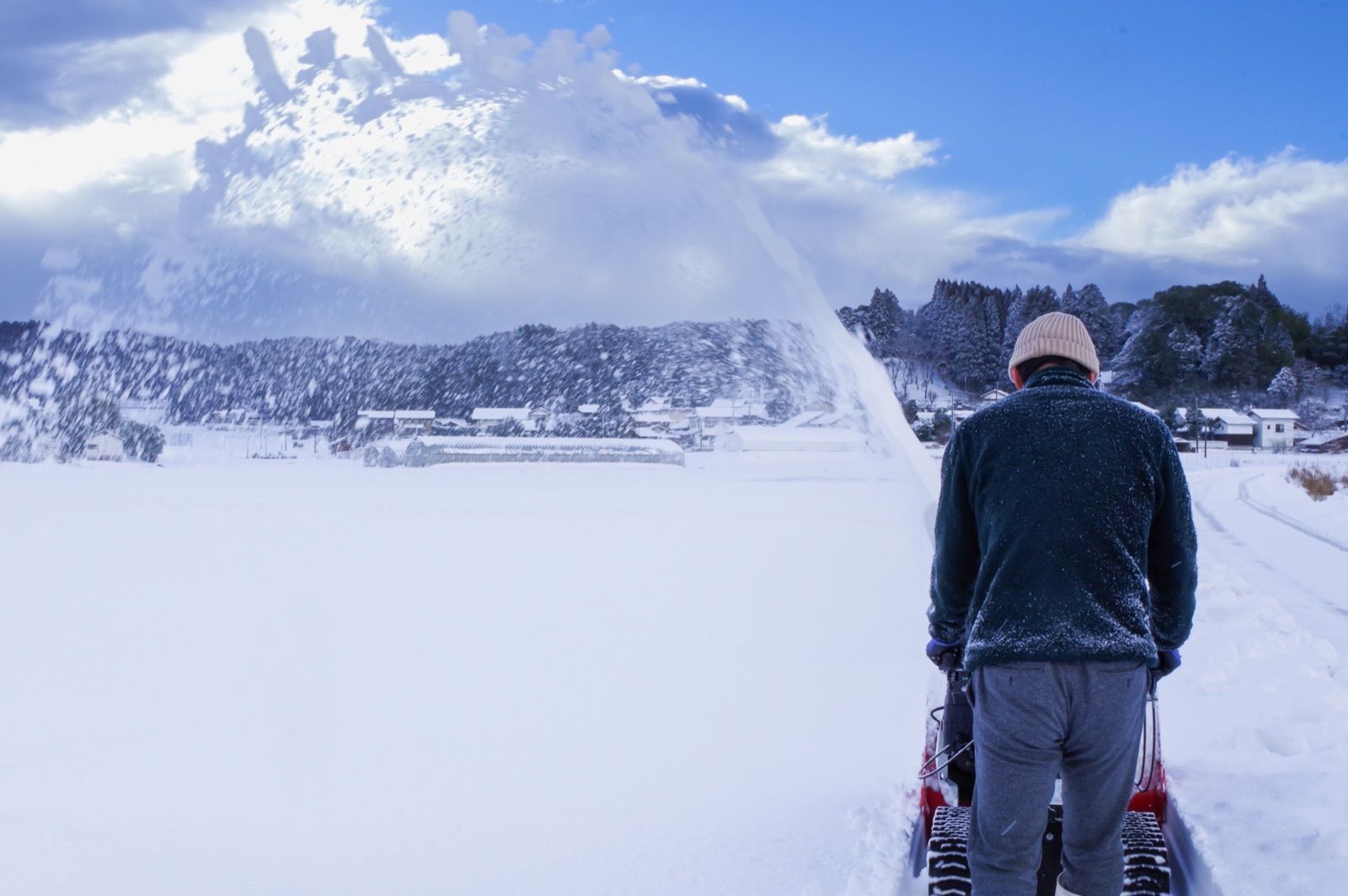 雪景色の中で除雪機を操作する様子（イメージ写真）
