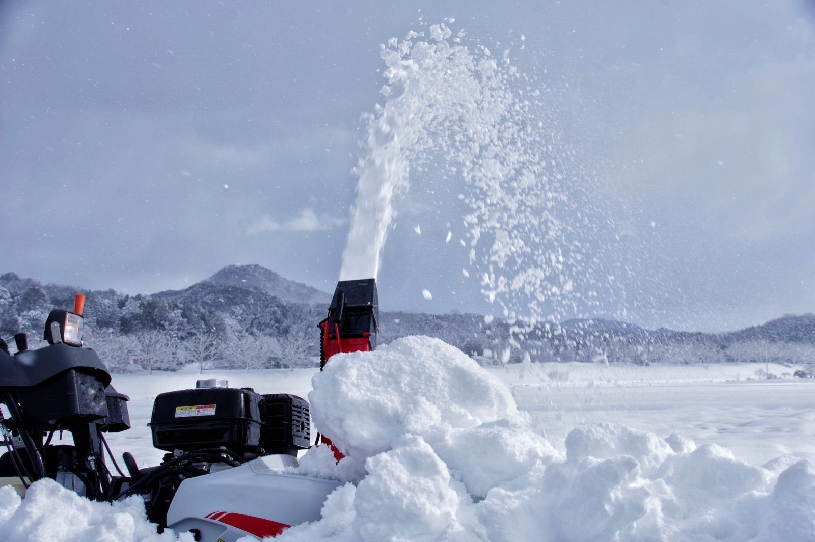 雪の中で投雪する除雪機(イメージ写真)